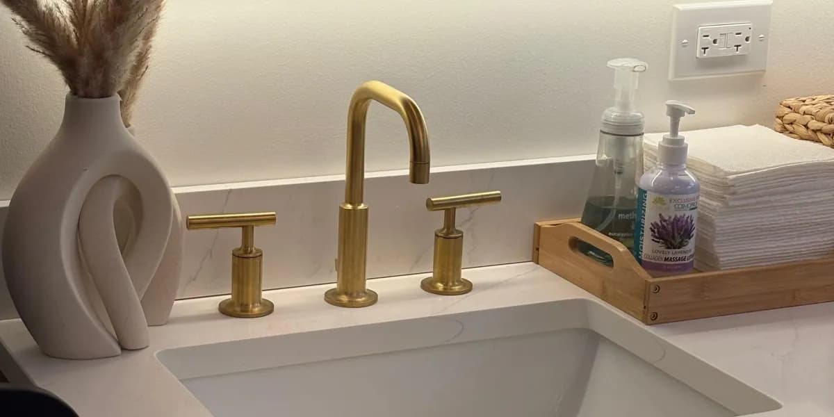 Gold faucet beside a sculptural vase and fresh towels at the salon